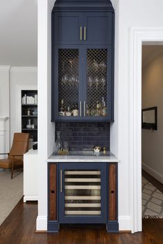 a kitchen with blue cabinetry and marble counter tops, along with an open door leading to the dining room