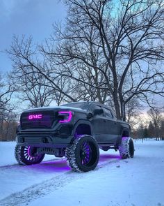 a black truck parked in the snow with purple lights on it's front tires