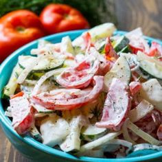 a blue bowl filled with salad next to tomatoes