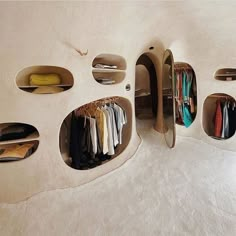 an unusual house made out of clay with holes in the wall and clothes hanging on shelves