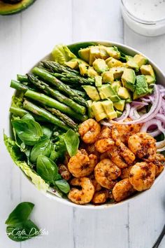 a bowl filled with shrimp, asparagus and avocado