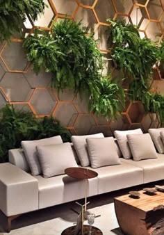 a living room filled with lots of furniture and greenery on the wall behind it