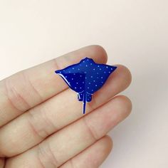 a blue pin with white dots on it in someone's left hand while holding something