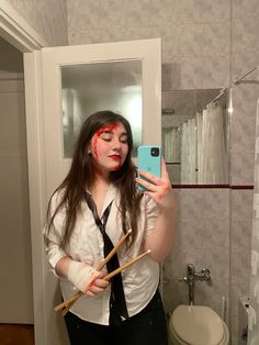 a woman with red makeup holding two sticks in front of her face and taking a selfie