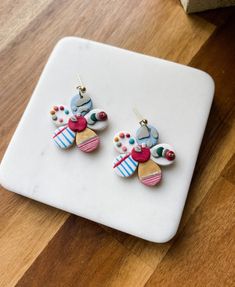 two pairs of colorful earrings sitting on top of a wooden table