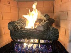 a fire burning in an outdoor fireplace with rocks