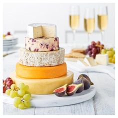 a cheese and fruit cake on a plate with glasses of wine in the background