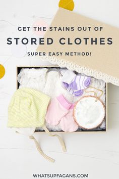 an open box filled with baby clothes on top of a white wooden table next to confetti