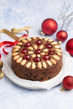 a chocolate cake with almonds and cherries on a plate next to christmas decorations