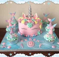 a birthday cake decorated with unicorns and cupcakes