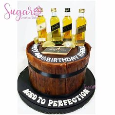 a birthday cake made to look like a barrel with three bottles of liquor on top