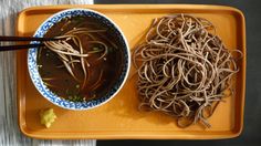 a bowl of noodles and chopsticks on a tray with a napkin next to it