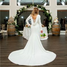 a woman in a white wedding dress standing on a wooden floor next to wine barrels