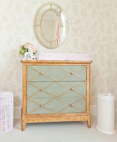 a baby's dresser and mirror in a room with floral wallpaper on the walls