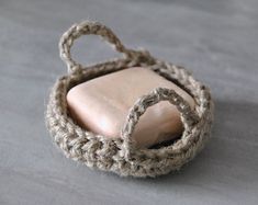 a crocheted basket with a stone in it on a gray surface, close up