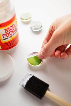 a person is holding a paintbrush and painting the inside of an egg with green food coloring