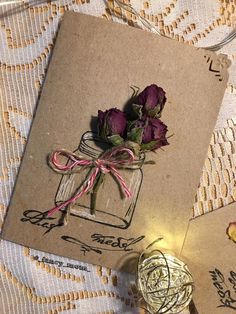 some flowers are sitting in a glass jar on a lace tablecloth with two tags