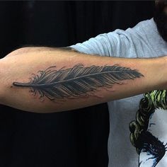 a man with a tattoo on his arm has a feather in the middle of it