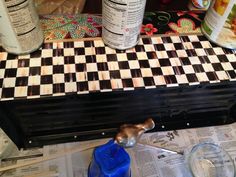 a checkered table top is being worked on with some glue and other crafting supplies