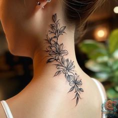 a woman's back neck tattoo with flowers on her left and behind her ear