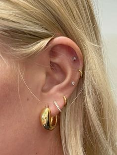 a close up of a person wearing some kind of gold earring with two diamonds