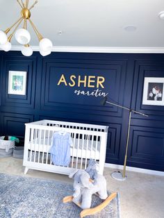 a baby's room with blue walls and white crib in the center, an elephant toy on the floor