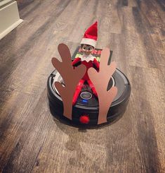 an elf is sitting on top of a robotic vacuum