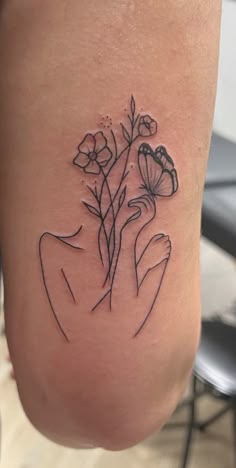 a woman's leg with flowers tattooed on the side and her hand holding it