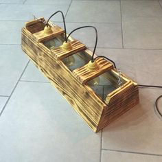 a wooden box with three bells attached to the front and sides, sitting on a tile floor