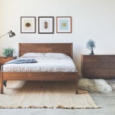 a bed sitting in a bedroom next to two nightstands with pictures on the wall