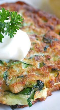 a close up of a plate of food with broccoli and sour cream on top