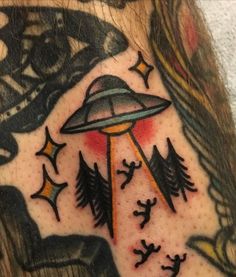 a man's arm with tattoos on it and an alien flying through the sky