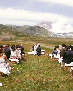 a group of people sitting on top of white folding chairs in the middle of a field