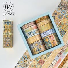 an assortment of decorative washi tapes in a blue box on a white surface with gold trim