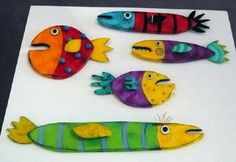 five brightly colored fish sitting on top of a white table next to another colorful object