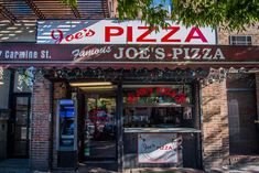 a pizza shop on the corner of a street in front of a building with an awning