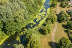 an aerial view of a river running through a lush green field next to a road