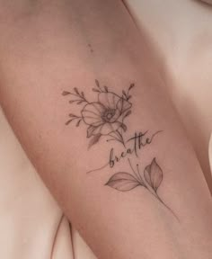 a close up of a person's arm with flowers on it and the words breathe written in cursive writing