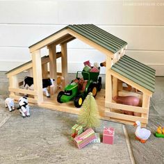 a toy farm house with animals and toys surrounding it on the floor in front of a garage