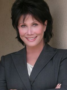 a woman with her arms crossed wearing a suit