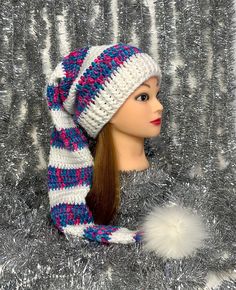 a female mannequin head wearing a knitted hat and scarf with pom - poms