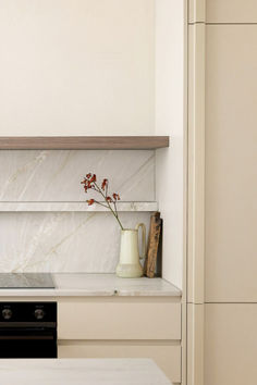 a vase with flowers sitting on top of a counter next to a stove and oven