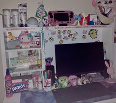 a desk with a computer and lots of toys on it's shelf next to a stuffed animal