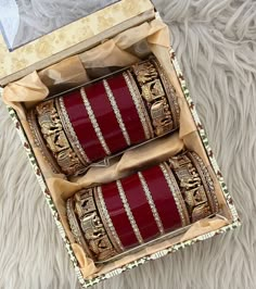 two red and gold bracelets sitting in a box on a furnishing floor