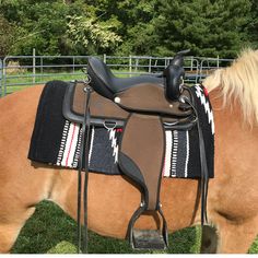 a brown horse wearing a saddle on top of it's back in the grass