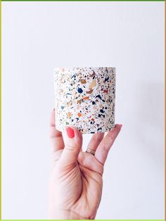 a woman holding up a white cup with sprinkles on it