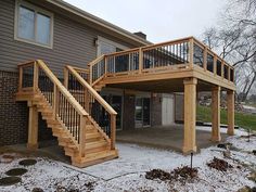 a wooden deck with stairs and railings in front of a house