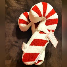 a red and white candy cane stuffed animal on a black blanket with a tag attached to it