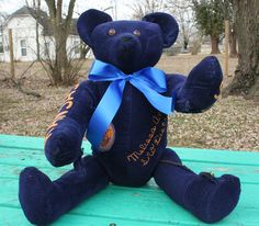 a black teddy bear with a blue ribbon around its neck sitting on a picnic table