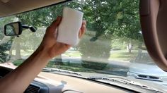 a person is holding something in their hand as they drive through the street and trees